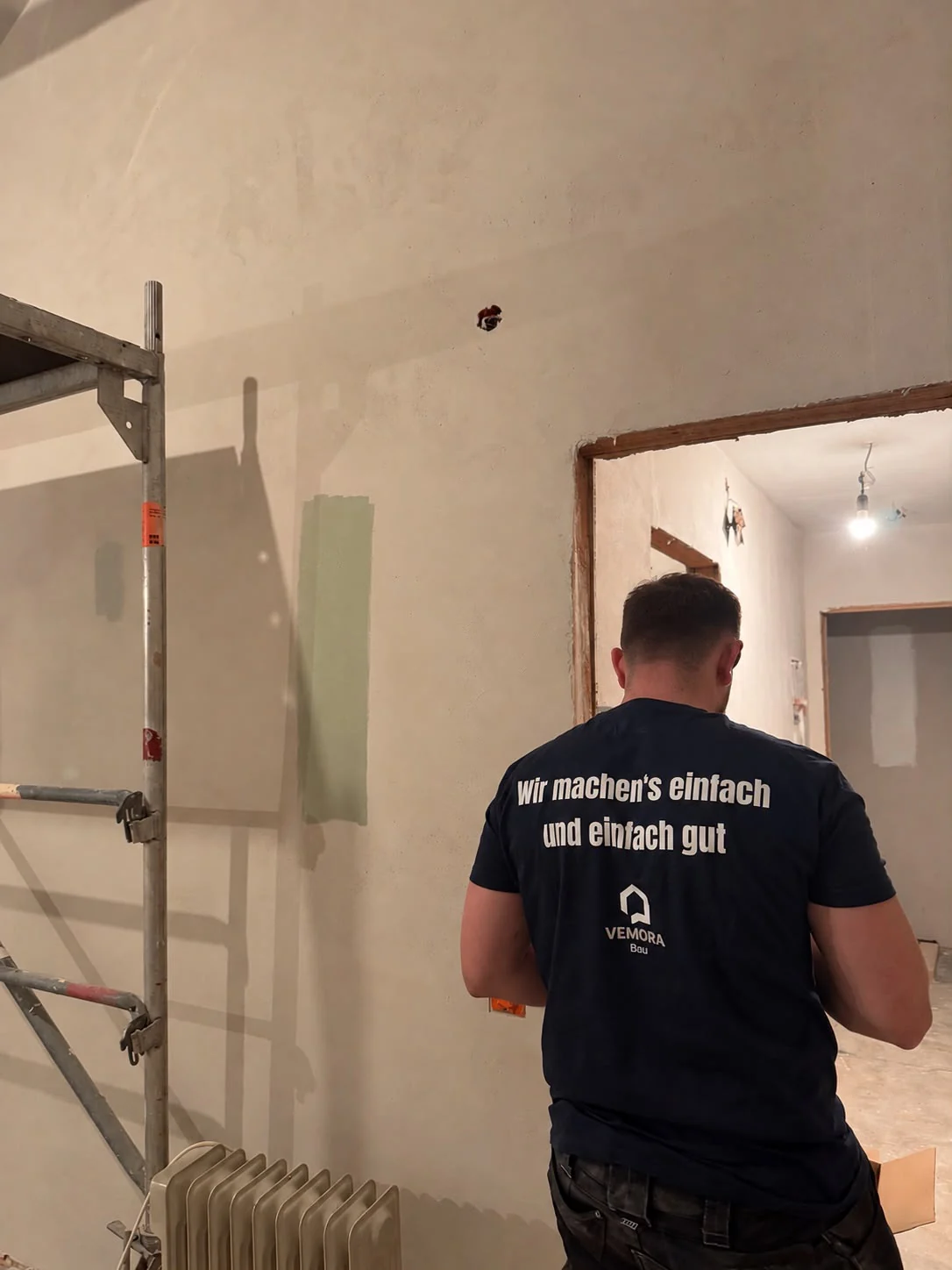 VemoraBau-Teammitglied bei Renovierungsarbeiten, mit dem Firmenslogan auf dem T-Shirt
